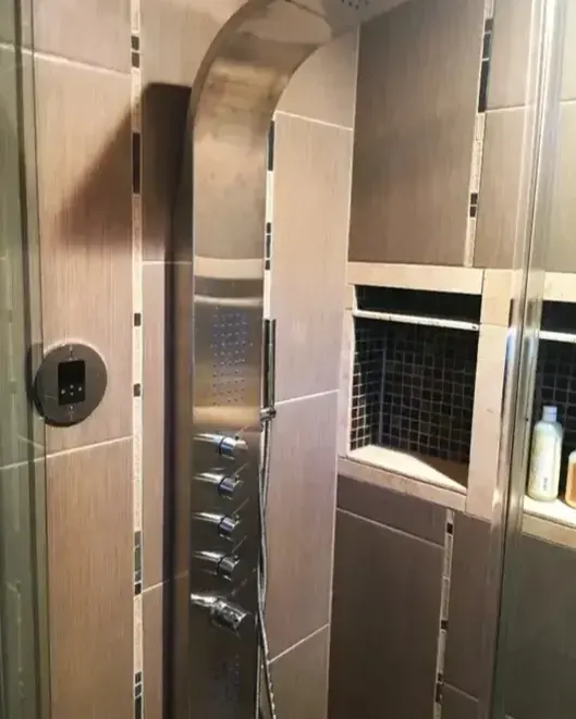 Tiled shower with a steel shower panel and built-in niches