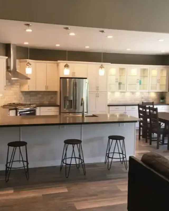 Kitchen with white cabinets, island seating and pendant lights