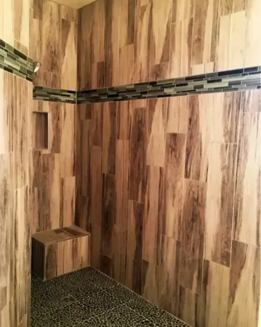 Walk-in shower with wood-look tile and a pebble floor